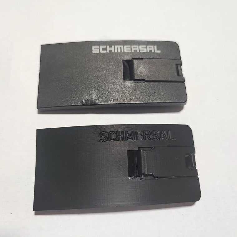 Dos tapas de interruptor de seguridad. Arriba, la original de fábrica, desgastada. Abajo, la que imprimió Proinn, con su grabado de marca en relieve