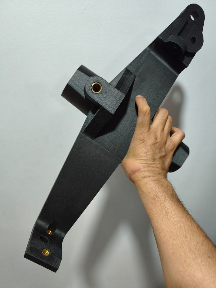 Brazo estructural negro con bujes de latón en el pivote, sostenido en la mano
