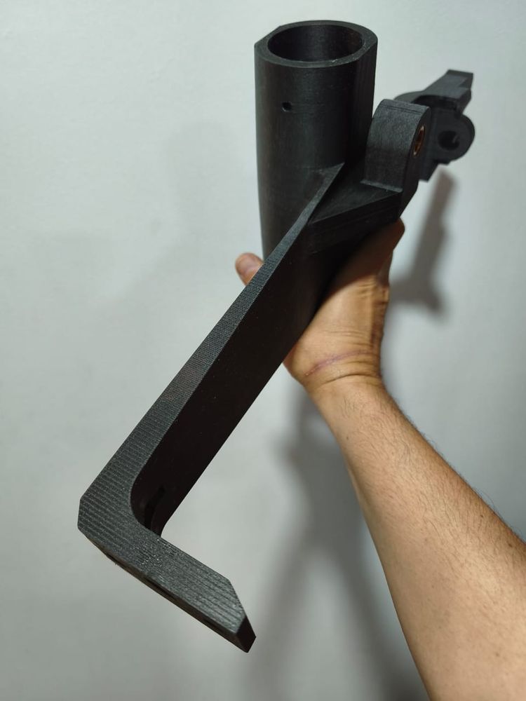 Brazo negro en forma de L sostenido en la mano; se ven las capas de impresión